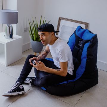 Man Plays Video Games on the PlayStation Official Bean Bag Chair in the Living Room 