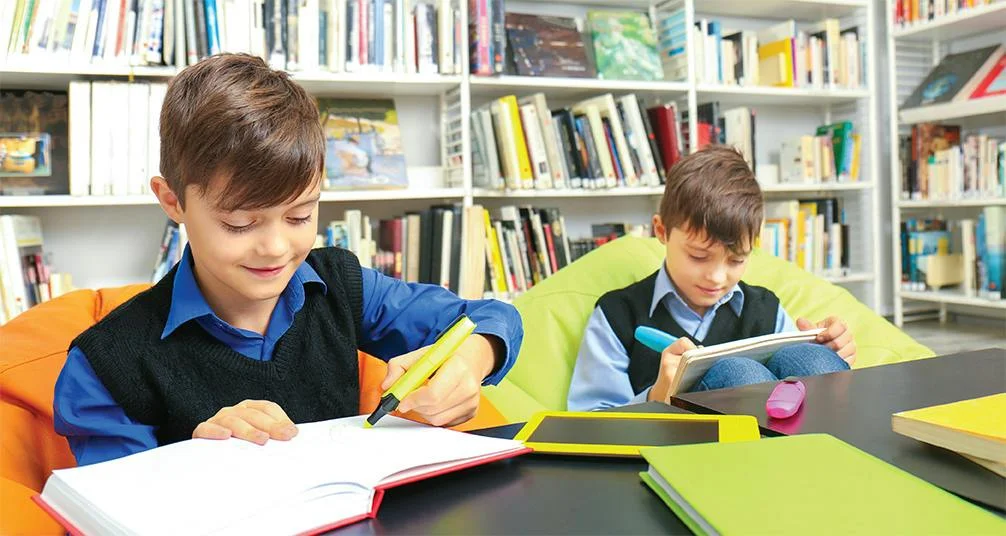 Child writing while sitting on beanbag in library